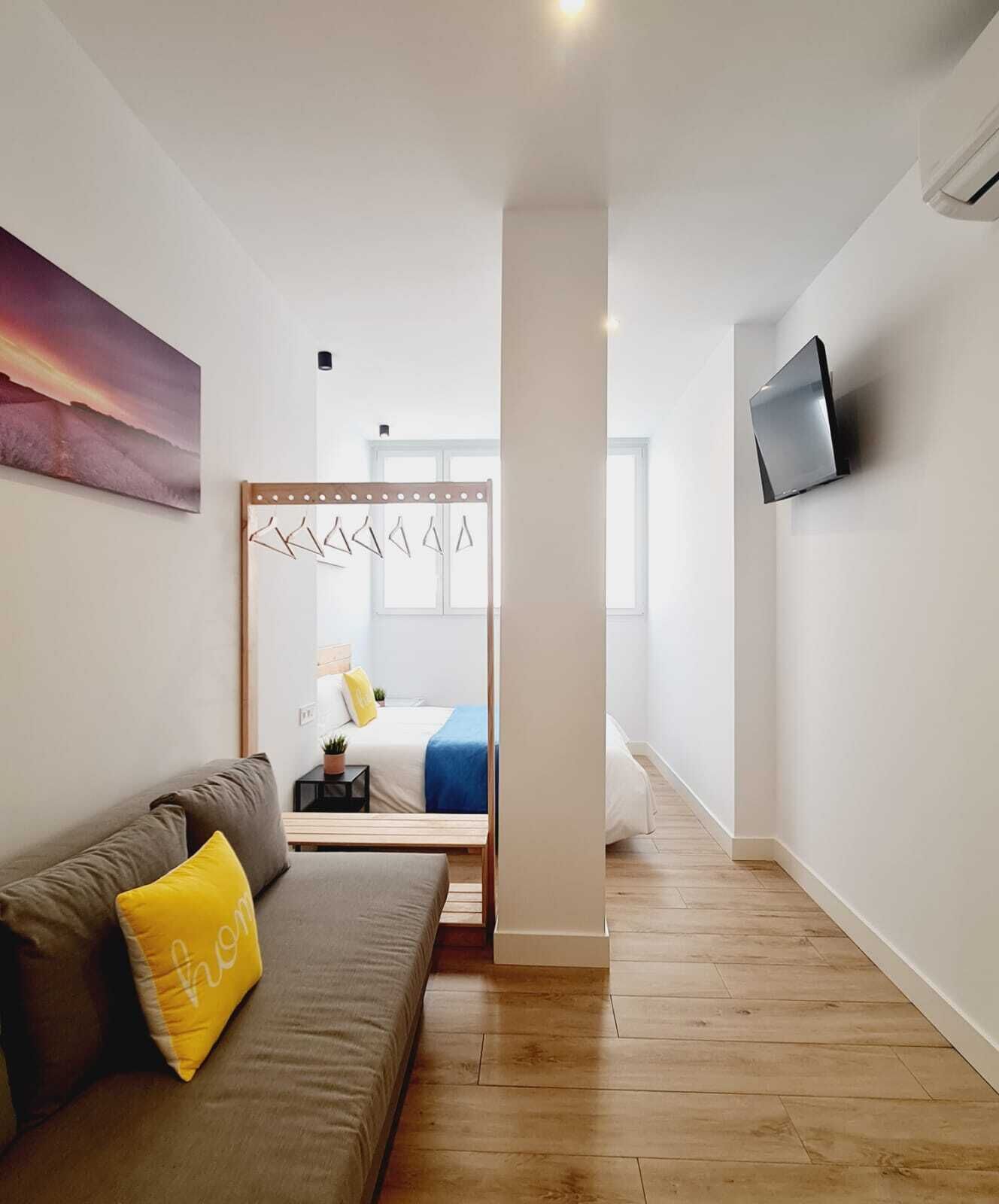 A modern interior with a sofa, a bed, a TV, and a wooden floor.