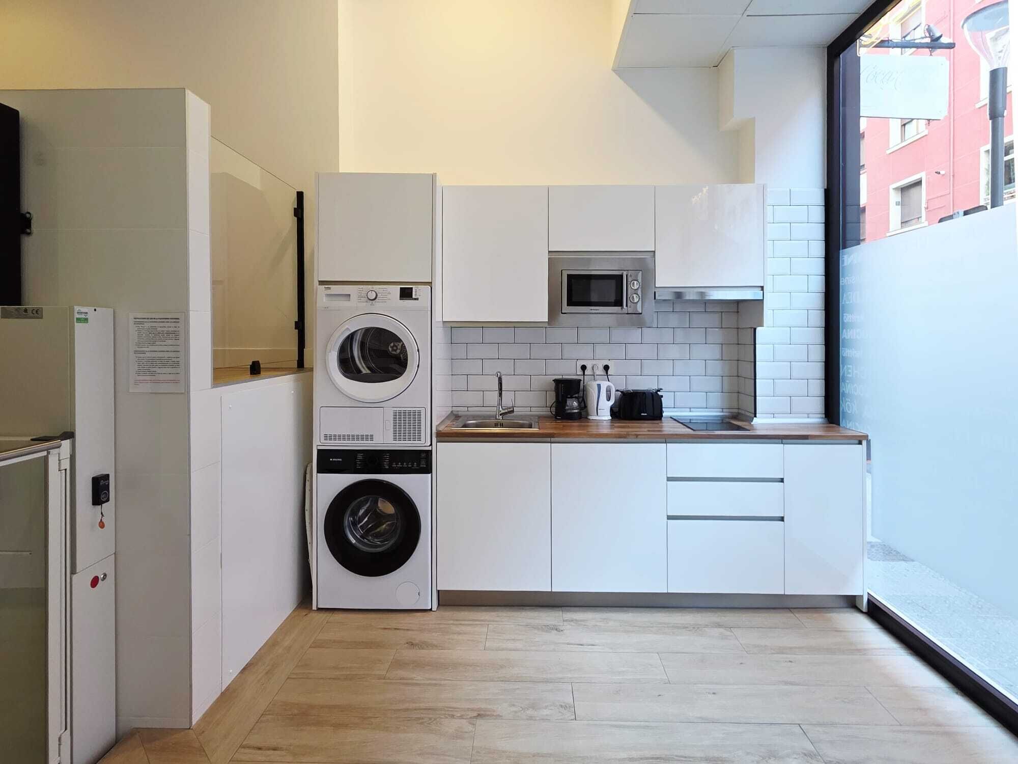 A compact kitchen with a washing machine, microwave, and a sink.