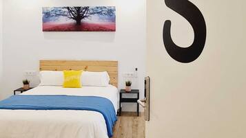 Quarto com cama, mesas de cabeceira, um criado-mudo, obra de arte na parede e um número grande na parede.