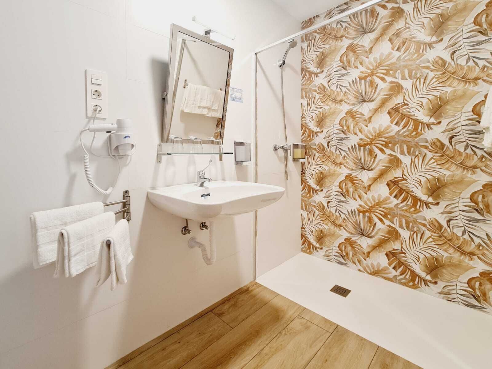 A bathroom with a sink, mirror, towel rack, shower curtain, and wooden floor.