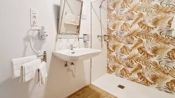 A bathroom with a sink, mirror, towel rack, shower curtain, and wooden floor.
