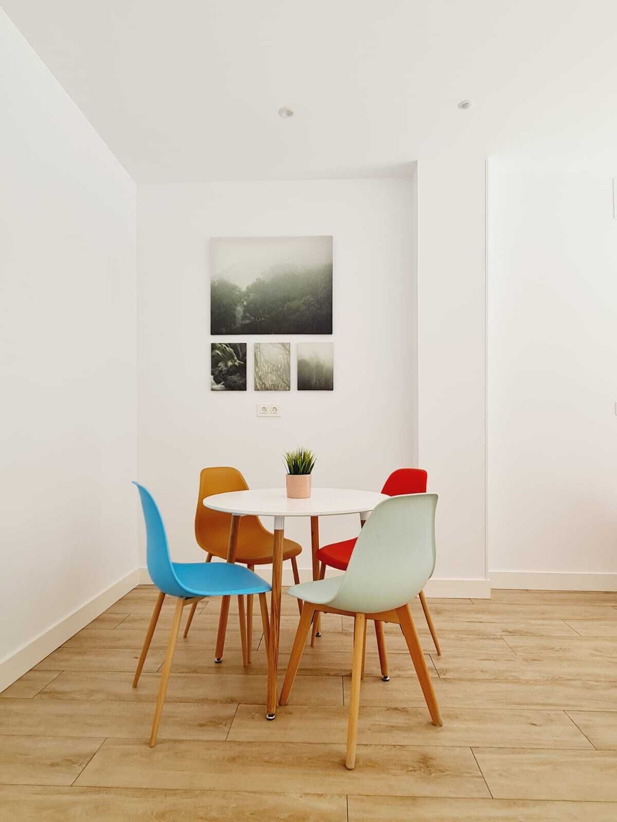 Un comedor moderno con una mesa redonda, sillas coloridas y una planta en maceta.