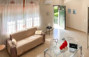 A modern living room with a beige sofa, a glass coffee table, and a view of a balcony.