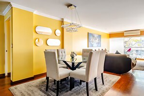 Uma sala de estar moderna com uma mesa de centro de vidro, duas cadeiras, um sofá e um candelabro.