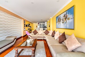 A modern living room with a sofa set, a coffee table, and a painting on the wall.