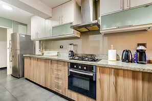 Una cocina moderna con refrigerador de acero inoxidable, horno empotrado, estufa a gas y alacenas de madera.