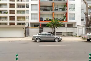 Ein modernes, mehrstöckiges Gebäude mit einem geparkten Auto davor.