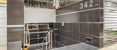 Una entrada moderna de edificio con puerta de vidrio, portón de metal y el número '342' en la pared.