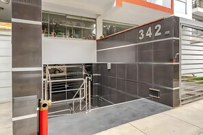 Una entrada moderna de edificio con puerta de vidrio, portón de metal y el número '342' en la pared.