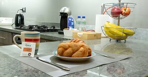 Eine Küchenarbeitsplatte mit einer Speisenplatte, einer Tasse, einem Bananenkorb und einer Kaffeemaschine.