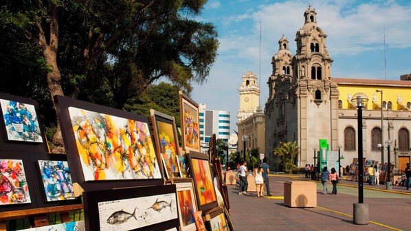 An outdoor art display with paintings in front of a historic church.