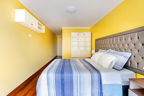 Habitación de hotel con cama, mesita de noche, lámpara, armario y ventana.