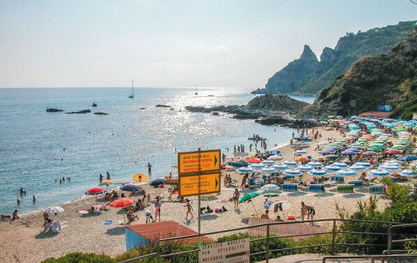Uma praia movimentada com muitos guarda-sóis e pessoas aproveitando o sol.
