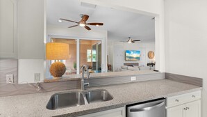 A modern kitchen with a granite countertop, stainless steel sink, and a dishwasher. - Vitamin Sea |Dog-friendly Spanish-style Townhome, Steps to SK Beach & Village (Siesta Key)