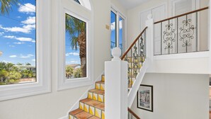 A staircase with patterned tiles, white walls, and a view of palm trees and houses. - Vitamin Sea |Dog-friendly Spanish-style Townhome, Steps to SK Beach & Village (Siesta Key)