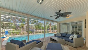 A covered outdoor area with a pool, wicker furniture, and a ceiling fan. - Banyan Tree Beach House | Updated Canal-Front Pool Home w/ Private Dock (Siesta Key)
