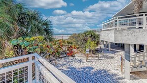 A beachside hotel with a concrete structure, a sandy beach, and tropical vegetation.