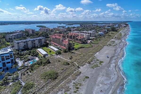 An aerial view of a coastal resort with multiple buildings, a beach, and a marina.