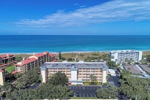 A hotel with multiple buildings, a parking lot, and a view of the ocean.