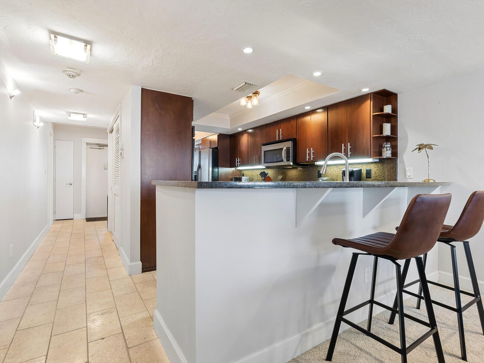 A modern kitchen with a central island, bar stools, and built-in appliances.