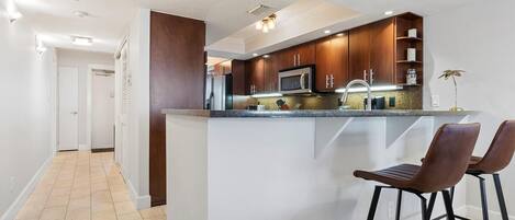 A modern kitchen with a central island, bar stools, and built-in appliances.