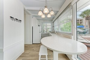 Une cuisine moderne avec un plan de travail blanc incurvé, un luminaire suspendu et un banc.