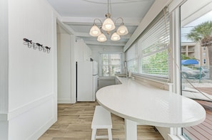 A modern kitchen with a curved white countertop, a hanging light fixture, and a bench.