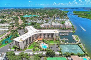 A hotel with a curved roof, multiple swimming pools, and a marina with boats.