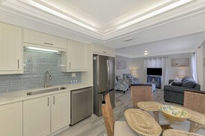 A modern kitchen with white cabinets, a stainless steel refrigerator, and a blue-tiled backsplash.