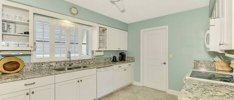 A kitchen with white cabinets, a granite countertop, a built-in oven, and a ceiling fan.