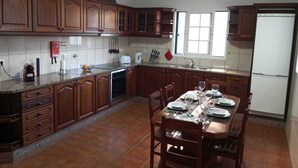 Une cuisine avec des meubles en bois, un pare-feu en carreaux, une table à manger pour quatre personnes et une fenêtre laissant entrer la lumière naturelle.