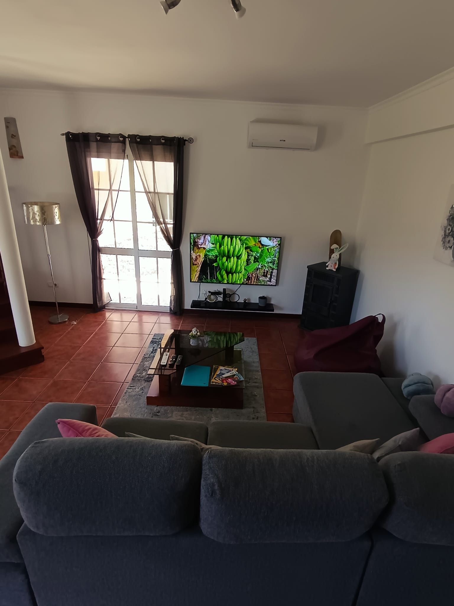 Un soggiorno con divano, televisione, camino e finestra con tende.