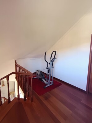 A staircase leading to a room with an exercise machine and a red rug. - Dotty's House (Santa cruz)