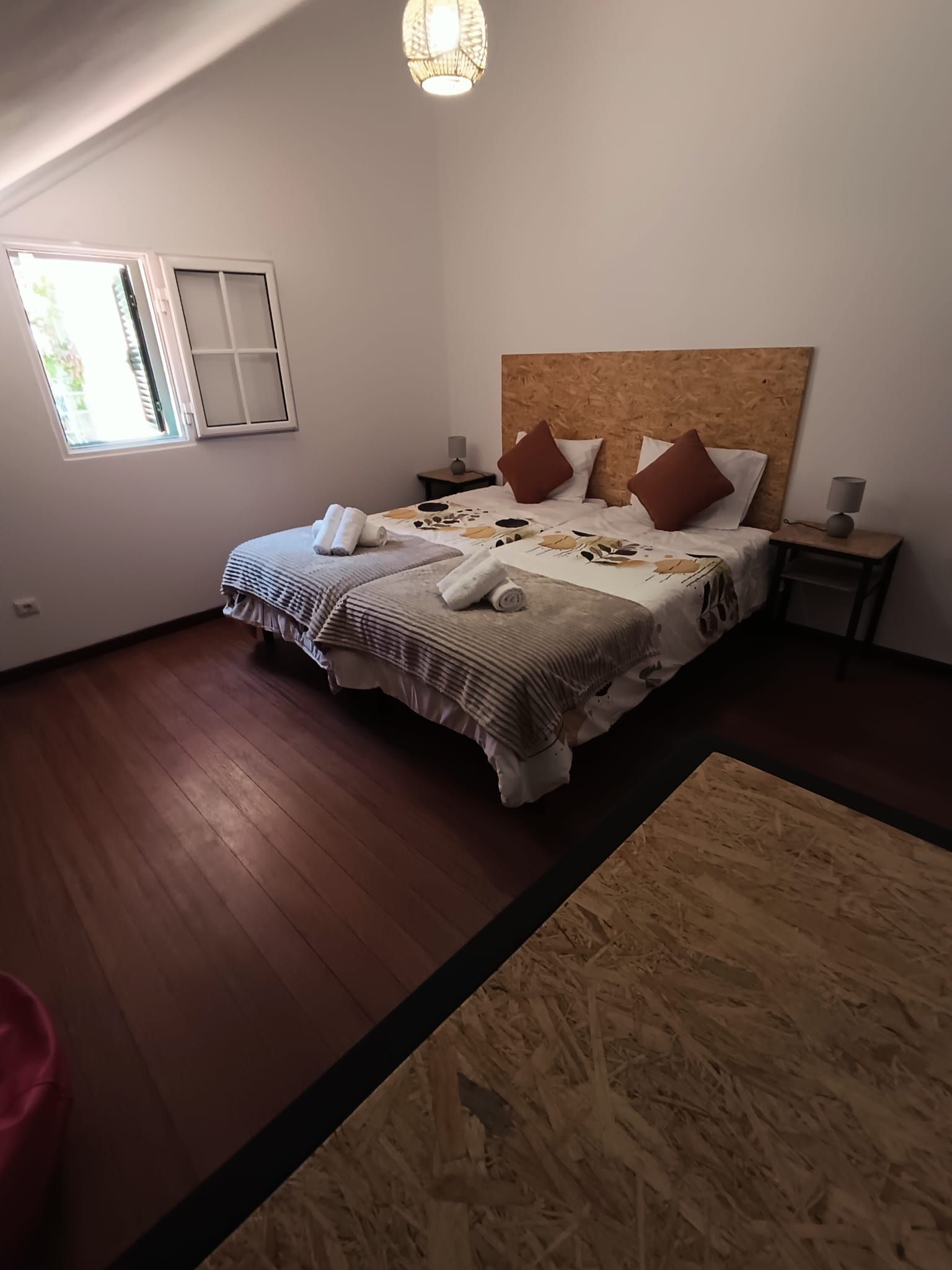 Ein Schlafzimmer mit einem großen Bett, zwei Nachttischen, einem Fenster und einem Holzboden.