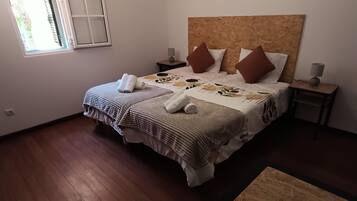 Ein Schlafzimmer mit einem großen Bett, zwei Nachttischen, einem Fenster und einem Holzboden.