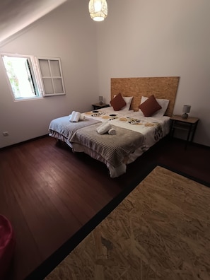 A bedroom with a large bed, two bedside tables, a window, and a wooden floor. - Dotty's House (Santa cruz)