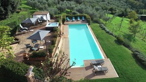 Ein rechteckiger Pool mit Holzterrasse und Liegestühlen.