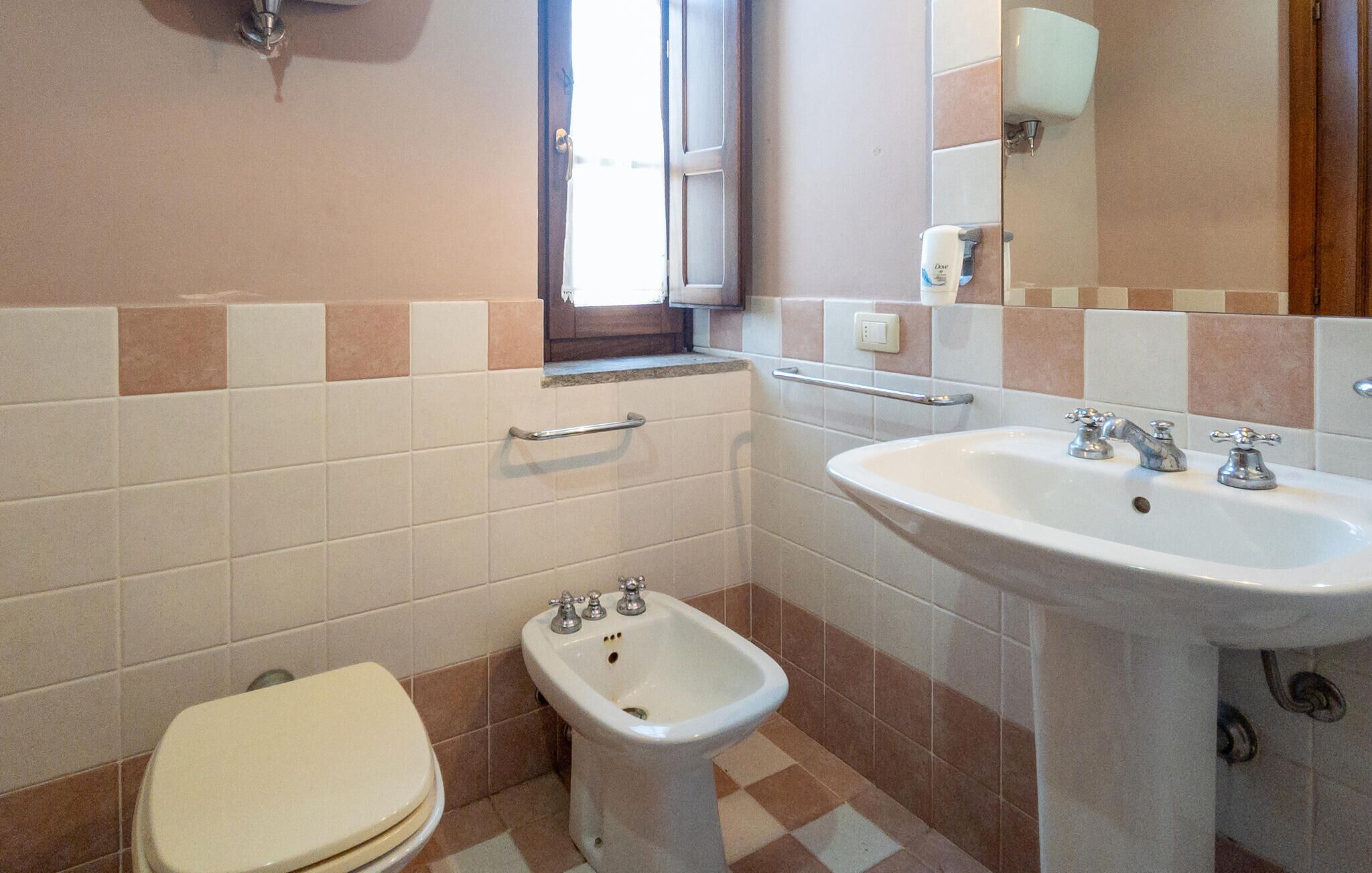 Une salle de bain équipée de toilettes, d’un bidet, d’un lavabo et d’un miroir.