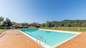 A rectangular swimming pool with a tiled deck, surrounded by a fence, and a gazebo in the background. - Lovely apartment in Montone with WiFi (Montone)