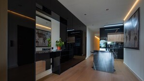 Una cocina moderna con armarios oscuros, una isla central y un comedor con una mesa larga.