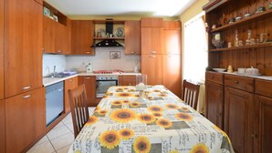 A kitchen with wooden cabinets, a stove, and a table covered with a sunflower tablecloth.