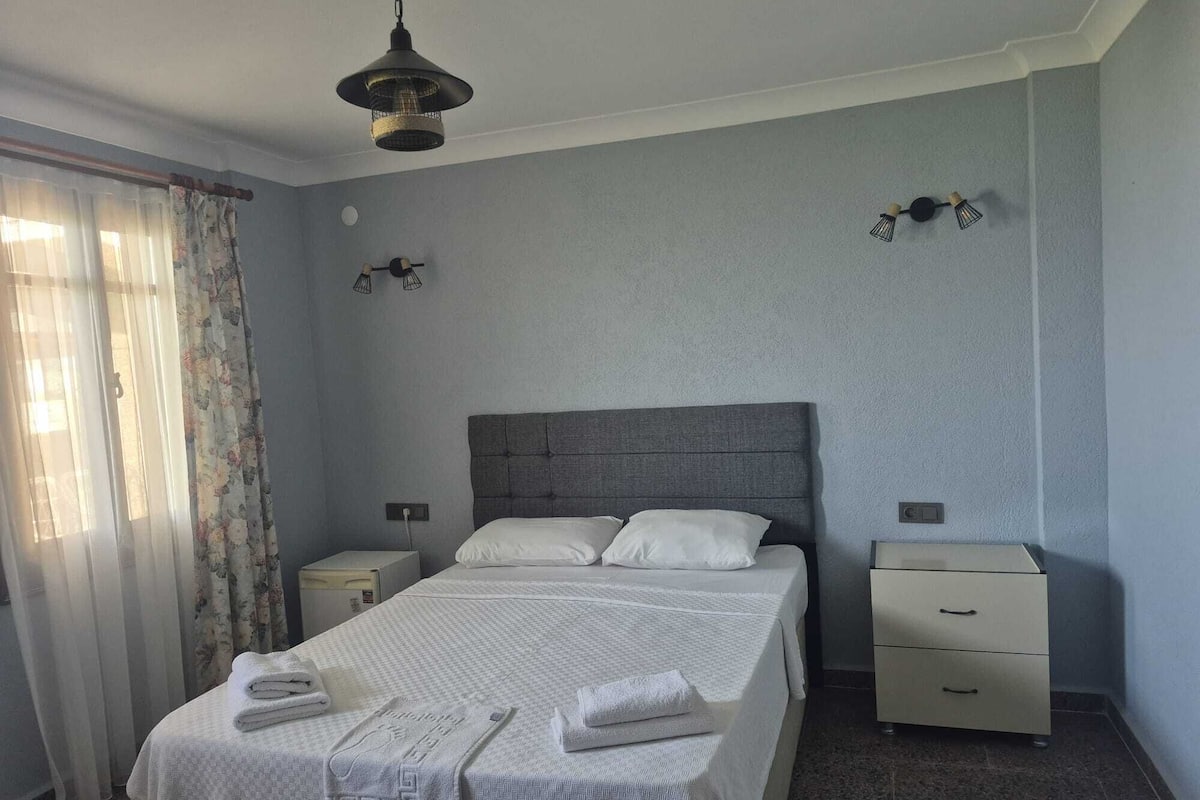 A neatly arranged bedroom with a bed, bedside tables, and a hanging light fixture.