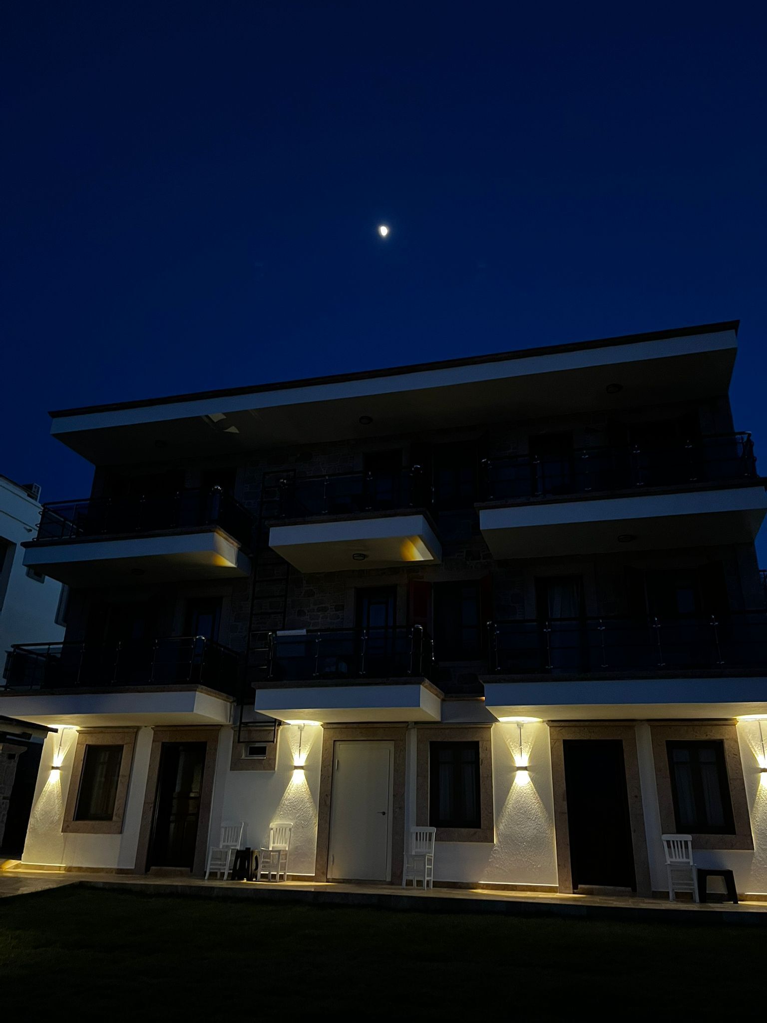 A multi-story building with balconies and exterior lighting.