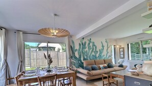 Ein modernes Wohnzimmer mit Essbereich, einer Couch und einer großen Wandkunst mit Kakteenmotiven.