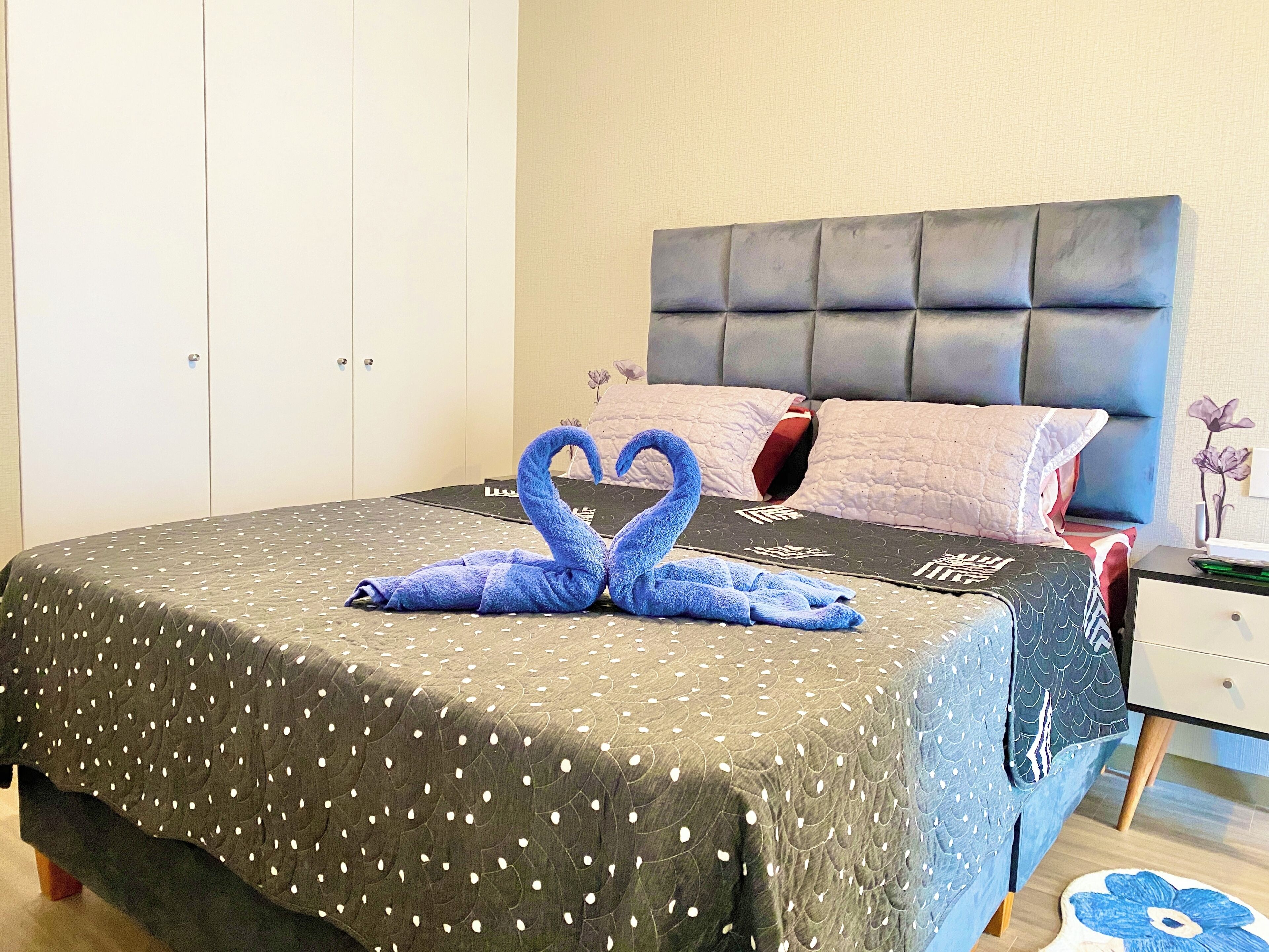 A neatly made bed with a polka dot bedspread and a blue towel swan decoration.