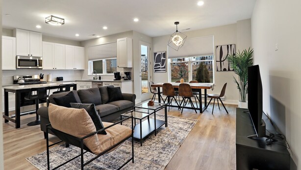 A modern kitchen with white cabinets, a built-in microwave, and a dining area with a table and chairs. - Warrenville Rep 2 (Warrenville)