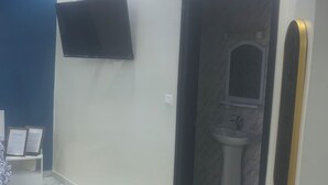 Une salle de bain moderne avec un sol en marbre, un téléviseur fixé au mur et un lavabo avec un miroir.