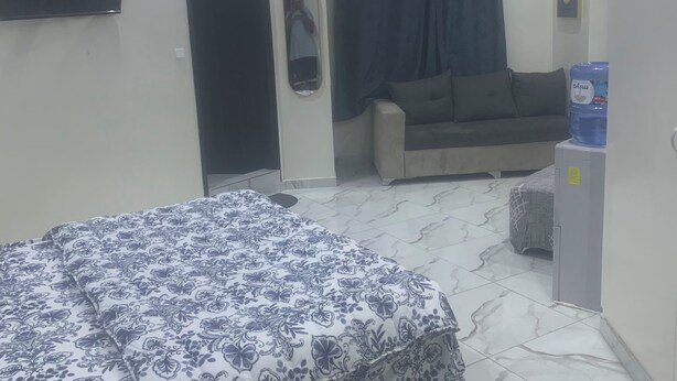 Une chambre comprenant un lit, un canapé, un téléviseur à écran plat, un appareil de climatisation et un distributeur d’eau.