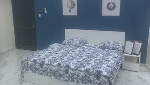Une chambre à coucher avec un lit, une table de chevet et deux tableaux encadrés accrochés au mur.