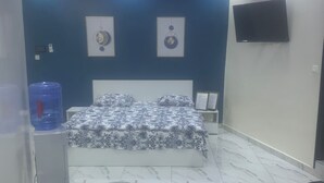 Une chambre avec un lit, un distributeur d’eau, un téléviseur à écran plat et une grande bouteille d’eau.